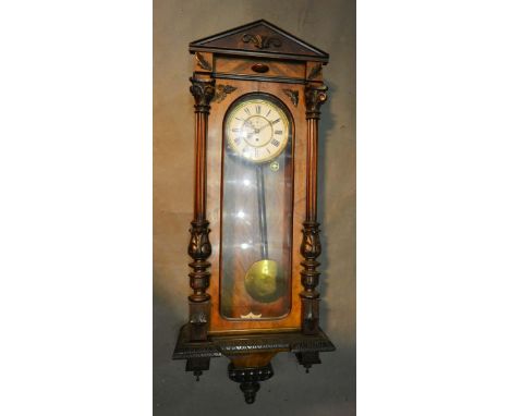 A Victorian Walnut Vienna Wall Clock, the enamel dial with Roman numerals and with weight driven movement, 123cm long 