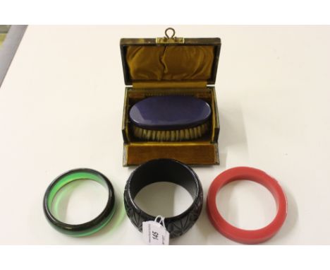 An Art Deco Bakelite bangle; together with coral pink and jade green bangles; and a boxed Art Deco brush and comb set 