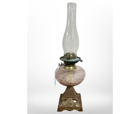 A gilt metal oil lamp with rose tinted clear glass reservoir.