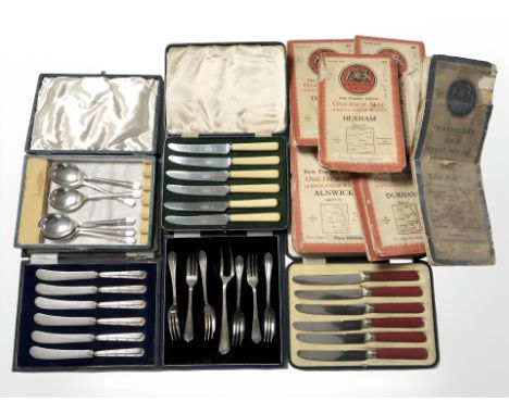 A group of boxed cutlery and several ordnance survey folding maps.