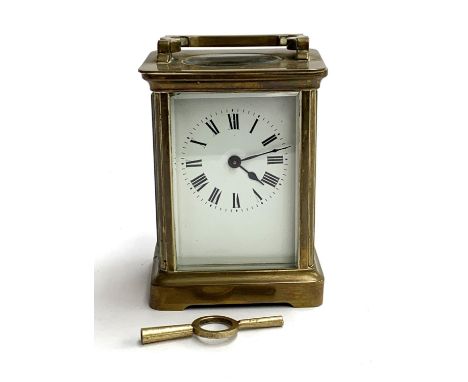 A brass carriage clock with bevelled glass and enamel dial with Roman numerals, 11cmH, with key 