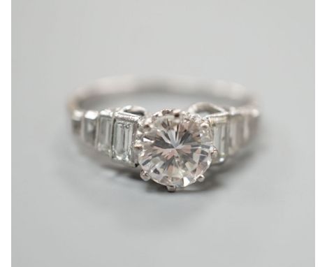 A white metal (stamped Plat) and single stone diamond ring, with graduated eight stone baguette cut diamond set shoulders, si