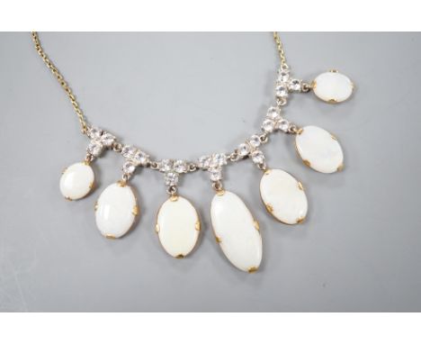 A yellow metal, graduated seven stone oval white opal and paste set cluster fringe necklace, 42cm, gross 14.6 grams.