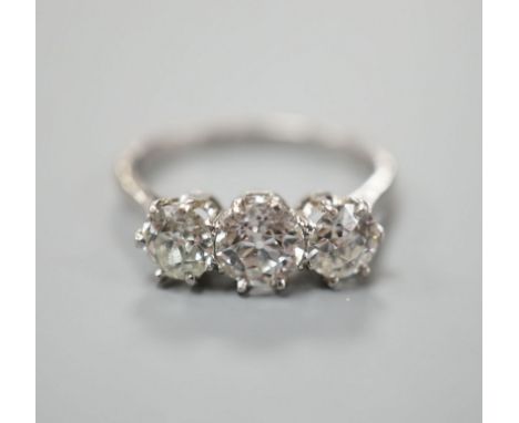 A white metal (stamped Plat) and three stone diamond set ring, size P/Q, gross weight 3.7 grams,the central stone weighing ap