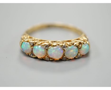 A late Victorian yellow metal and graduated five stone white opal set half hoop ring, with diamond chip spacers, size M, gros