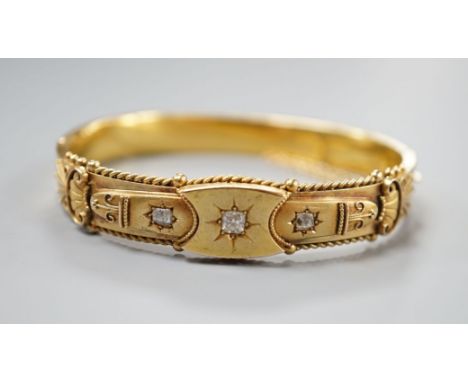 An Edwardian 15ct gold and three stone diamond set hinged bangle, interior diameter 57mm, gross weight 15.8 grams.