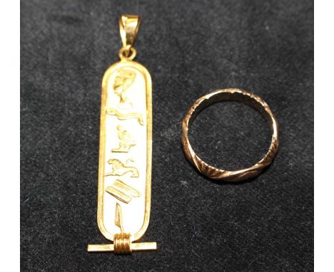 Two pieces of yellow metal jewellery featuring an Egyptian cartouche pendant and a patterned band ring. The pendant bears Egy