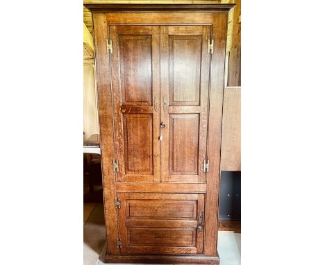 A George III and later oak hall livery cupboard, swept cornice above twin moulded panel doors enclosing three fitted shelves,