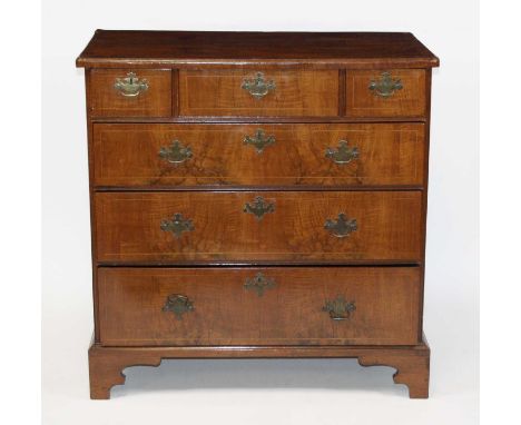 A George II walnut chest, having a crossbanded top above three short and three long graduated drawers, on later bracket feet,