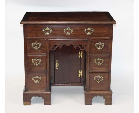 A George III mahogany kneehole desk, having an arrangement of seven drawers above a kneehole cupboard, all raised on replacem