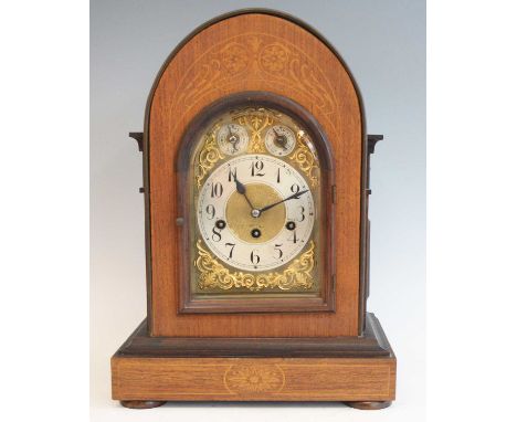 An Edwardian Yunghans mantel clock, having an arched brass dial with silver chapter ring, triple winding holes for an eight-d