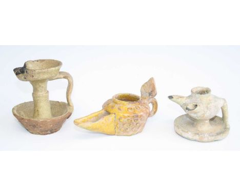 A yellow tin glazed pottery oil lamp, the body with incised and applied dot decoration, having an elongated spout with loop h