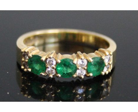 An 18ct yellow gold, emerald and diamond half hoop eternity ring, comprising three round faceted emeralds alternating with fo
