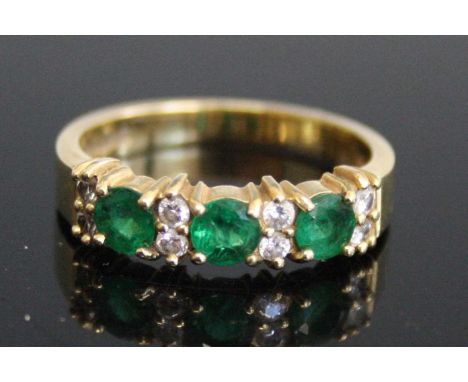 An 18ct yellow gold, emerald and diamond half hoop eternity ring, comprising three round faceted emeralds alternating with fo