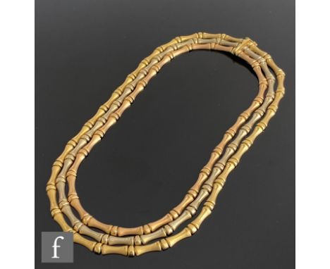 An 18ct hallmarked three strand necklace comprising rose, white and yellow gold articulated rows of waisted panels terminatin
