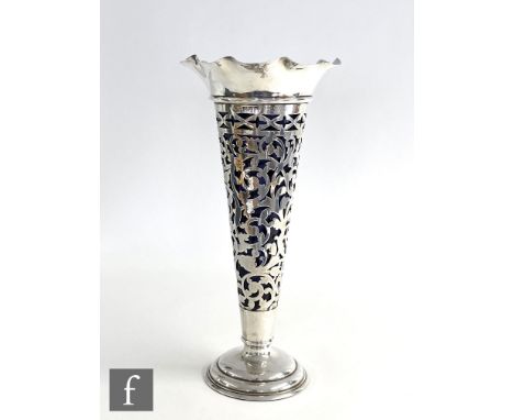 A hallmarked silver trumpet vase, circular stepped foot below foliate pierced body and crimped rim, all supporting blue glass