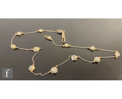 A silver on gold diamond set chain, comprising twelve individually brilliant cut, claw set stones to a fine trace chain, tota