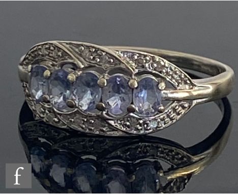 A 9ct hallmarked white gold tanzanite and diamond ring, five oval tanzanite within a pave diamond set border, weight 2.4g, ri