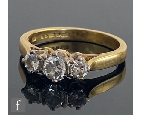 An 18ct diamond three stone ring, claw set brilliant cut stones, total weight approximately 0.70ct, to knife edged shoulders,