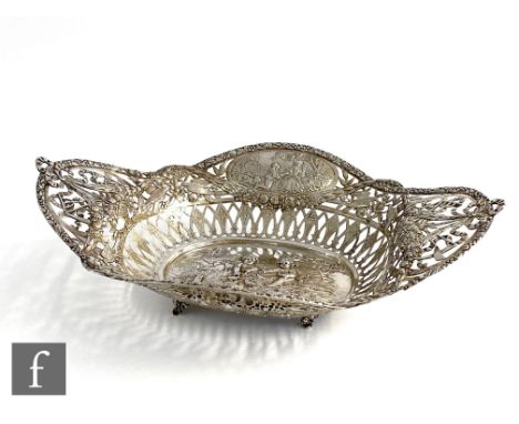 A late 19th Century continental silver oval bread basket decorated with embossed cherubs to a landscape setting to the well, 