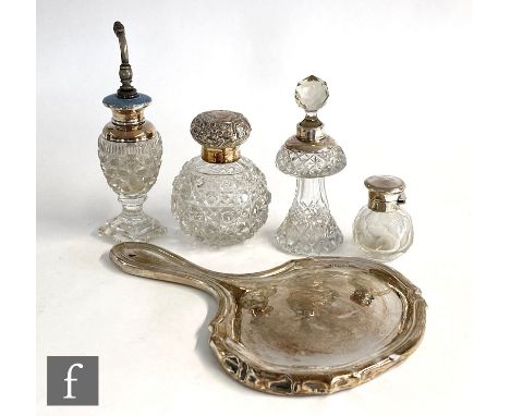 Three hallmarked silver clear cut glass scent bottles, an atomiser and a silver backed hand mirror, S/D. (5) 