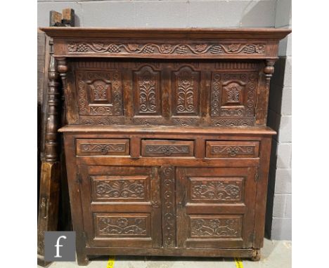 An 18th century and later carved oak court cupboard, the arched paneled back below a frieze decorated with trailing grapes an