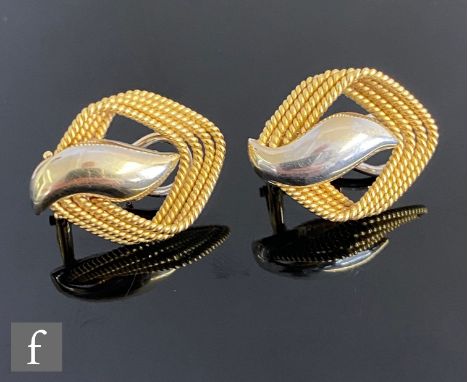 A pair of 18ct two coloured gold stud earrings with a central white gold scroll within a four strand rope twist surround, tot