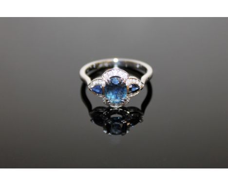 A 14ct white gold sapphire and diamond ring, an oval-cut deep-blue sapphire weighing 0.83 carat, between two tear drop deep-b