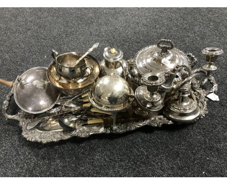 A silver plated twin-handled serving tray containing  a quantity of silver plated ware including candelabrum, sugar sifter, c