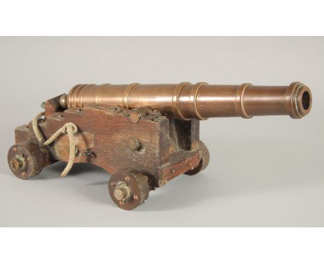A GOOD SMALL BRONZE CANNON on a wooden carriage with four wooden wheels.