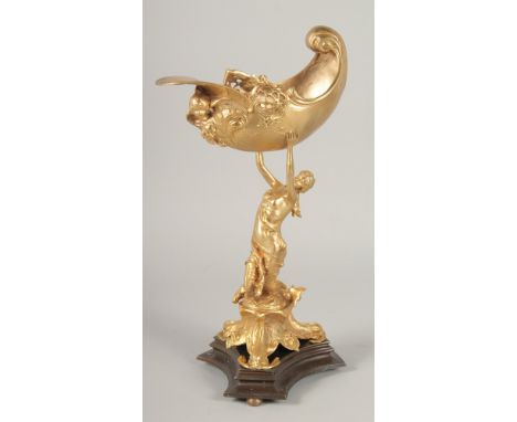 A GILT BRONZE COMPORT, a lady holding a shell on a triangular base. 1ft 3ins high.