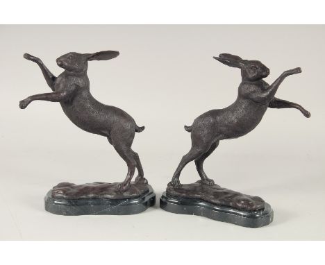 A PAIR OF BRONZE FIGHTING HARES on marble bases. 4ft 4ins high.