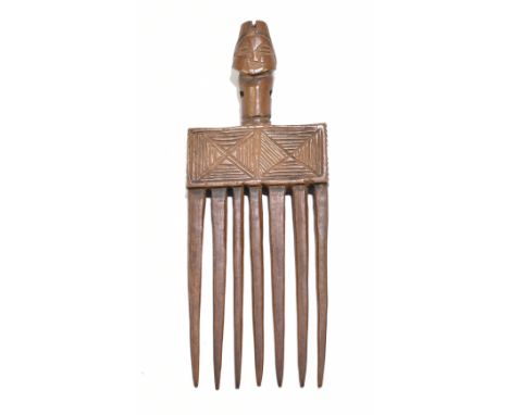 A late 19th/early 20th century African tribal comb with seven tines, incised decoration to the main frame and with stylised f