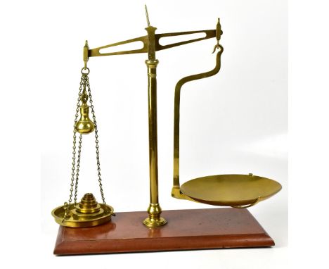 A pair of De Grave Short &amp; Co brass scales on stained rectangular wooden base, with pendulum-style weight hanging on a ch