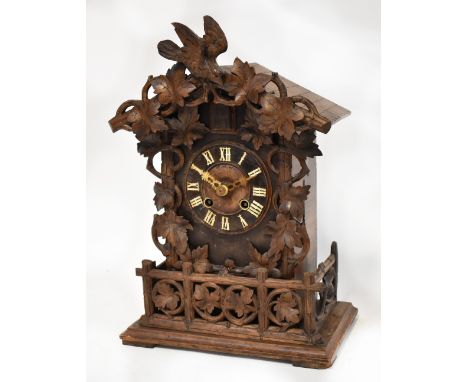 A late 19th century Black Forest bracket cuckoo clock, the dial set with Roman numerals, within an ornate carved oak leaf cas