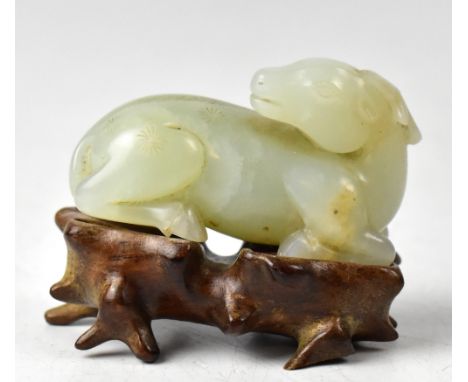 A Chinese jade model of a buffalo lying down, with its head over its shoulder, width 6cm, on a wooden stand. CONDITION REPORT