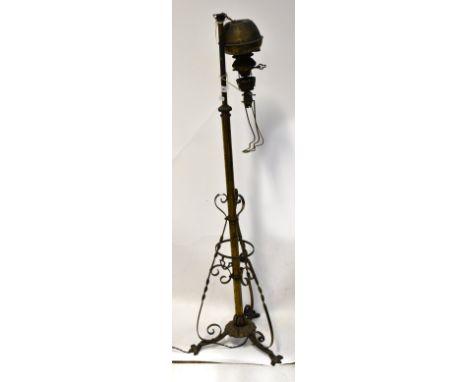 An Edwardian metal floorstanding oil lamp, converted to electricity, with central column supported on three scroll feet, heig