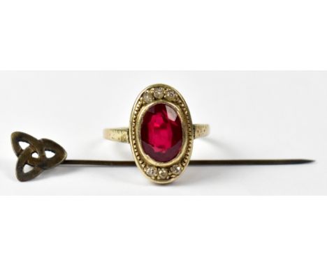 A 9ct yellow gold ladies' dress ring set with oval faceted red stone, tests as ruby, with three small white stones to mount, 