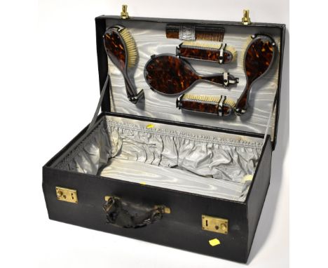 A large black vanity travel case with frilled satin pockets to the inside, the lid fitted with a six-piece pewter and faux to