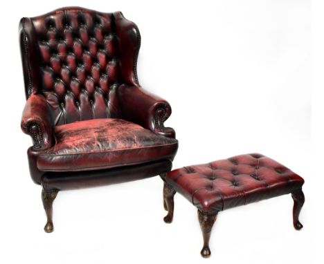 A Georgian style button back wing armchair, upholstered in oxblood leather with studs, on carved cabriole legs, width 87cm, a