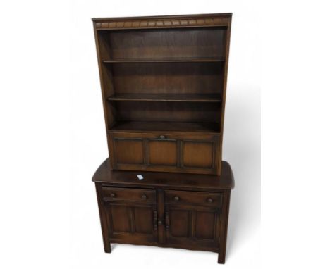 A dark Ercol dresser, the top with three shelves and fall front, to the base two drawers and a cupboard, with applied blue Er