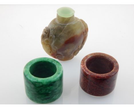 Two Chinese jade archer's rings, and a jade snuff bottle with dragon carving to shoulders. W. 5cm (3)