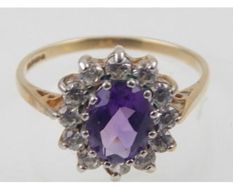 A 9ct yellow gold amethyst dress ring, the oval faceted stone with diamond border. 