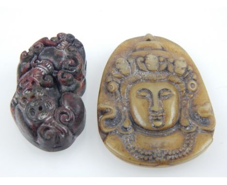 A Chinese spinach jade pendant carving of a god's face, H. 4.8cm, and a red / black jade pendant carving of a dragon. H. 3.9c