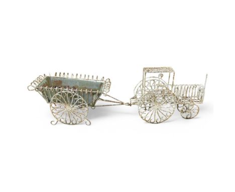 A weathered and painted wrought iron garden planter ornament, in the form of a tractor and trailer with galvanised metal line