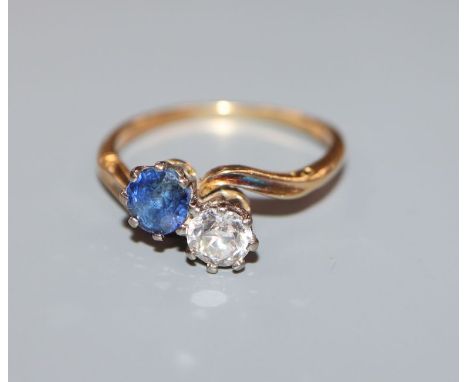 A mid 20th century yellow metal, two stone sapphire and diamond crossover ring, size L.