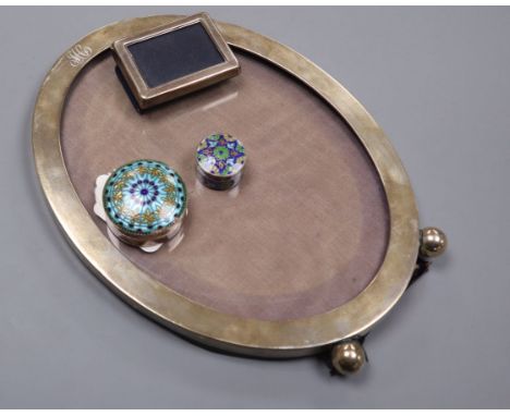 A sterling oval easel photograph frame on bun feet, a small silver frame and two miniature white metal and enamel boxes inclu