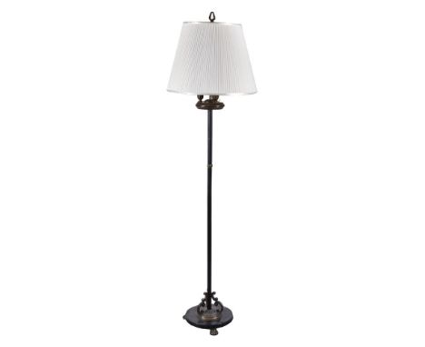 A gilt and patinated metal standard lamp, circa 1930, the pleated fabric shade above three electrical fitments, the reeded st