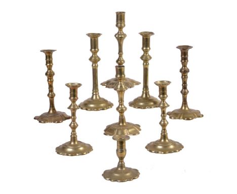 A pair of George II brass petal base candlesticks, mid 18th century, the ribbed urn sconces leading to incised and multi-knop