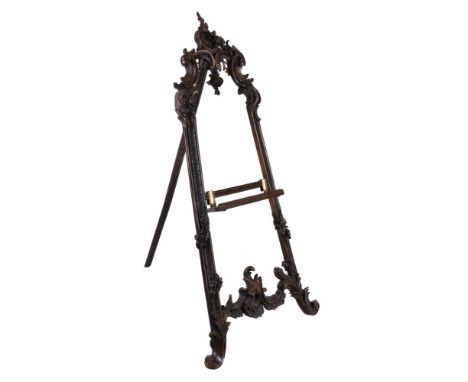A Continental carved and stained walnut A-frame gallery easel, first half 20th century, with scrolling foliate and rocaille m